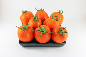 Tomato in black dish on on white background isolated.