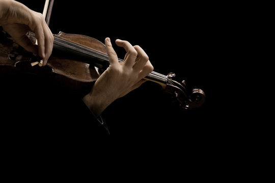 The violin in the hands of a musician closeup on a black background