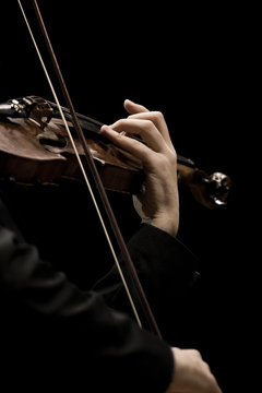 The violin in the hands of a musician closeup on a black background