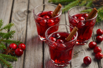 Cranberry drink on wooden background with fir branches and fresh berries, selective focus