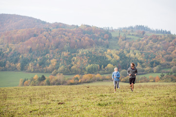 Fototapeta na wymiar Beautiful young couple running in sunny autumn nature.