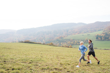 Fototapeta na wymiar Beautiful young couple running in sunny autumn nature.