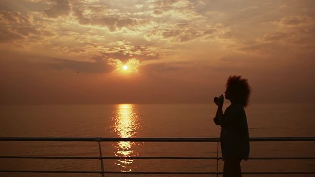 Beautiful female phorograph taking picture of sunrise at sea Slow motion