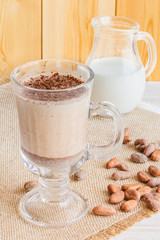 Fresh Made Chocolate Banana Smoothie on a wooden table with coffee and spices. Milkshake. Protein diet. Healthy food concept. Drink, cocoa beans, chocolate.