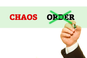 Hand writing CHAOS and ORDER word on a transparent wipe board.