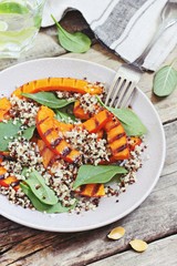 Quinoa salad with grilled pumpkin and fresh spinach on a rustic wooden table.Superfood and clean eating concept. Selective focus  © losangela
