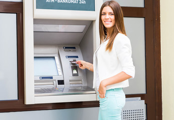 Fototapeta na wymiar young woman inserting credit card to ATM