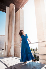 lady in blue dress posing near columns