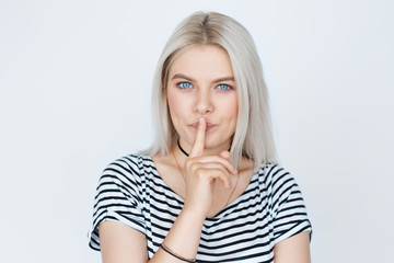 Portrait of beautiful blond woman with finger on lips