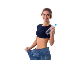 Woman wearing jeans of much bigger size and holding a bottle of 