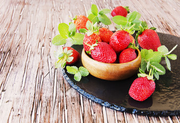 ripe red raspberries and strawberries in wooden bowl, selective focus