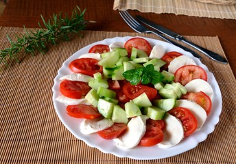Fresh vegetable salad with mozzarella and basil on a plate