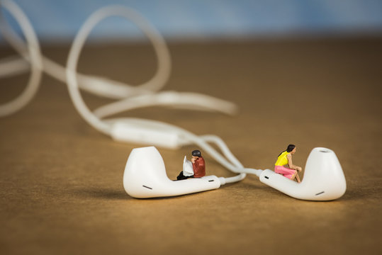 Miniature Figures Sitting on Earbuds listening to Music