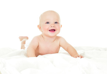 Beautiful smiling baby lying on his stomach in bed. One, isolate
