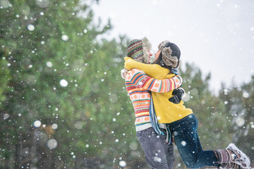 A loving couple walking in winter park. The snowfall