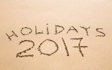 Happy Holidays 2017. Written in sand at the beach. Holiday, Christmas, New Year 2017 concept.