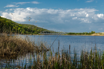 A beautiful Blue Lake with yellow grass in the foreground and a blue sky with clouds