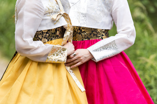 Two Korean girls dressed in traditional dress in a park