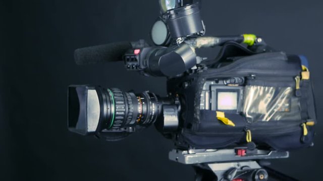 Camera operator working with a cinema broadcast camera at the unrecognizable tv news studio. 4K.