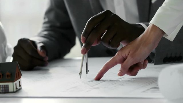 Young black architect working on construction blueprint in white office, he draws with a divider and ruler. Slow motion