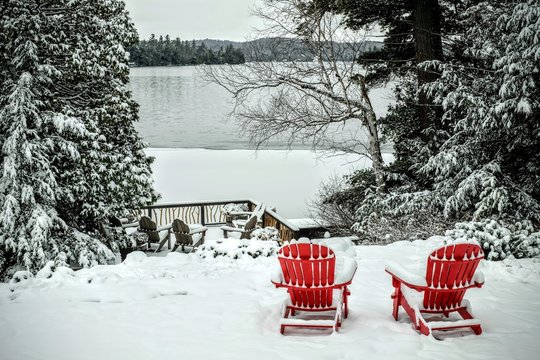 Pair of wooden adirondack chairs in the snow in front of the fro