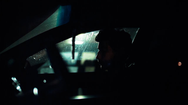 Profile of a man in a car on a dark night. Noir style