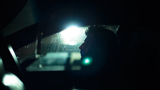 Profile of a man in a car on a dark night. Noir style
