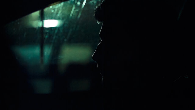 Profile of a man in a car on a dark night. Noir style