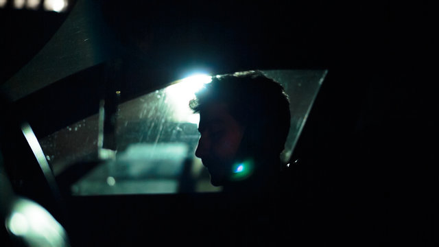 Profile of a man in a car on a dark night. Noir style