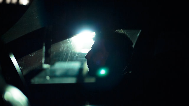 Profile of a man in a car on a dark night. Noir style