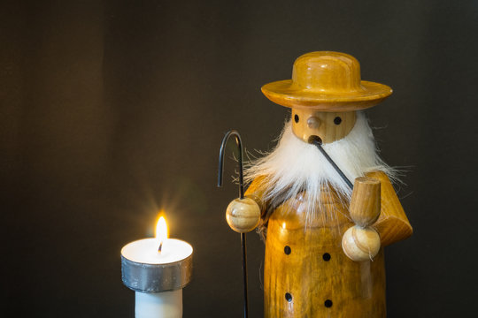 Räuchermännchen und Kerze vor einem schwarzen Hintergrund in der Weihnachtszeit