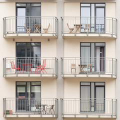 Modern new building with balconies full of tables, chairs - 123267988