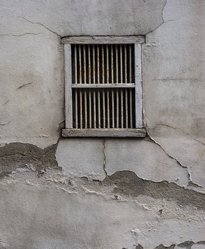 Barred window on old cracked concrete plaster wall grunge background