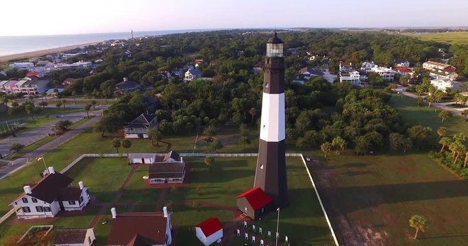 Aerial perspective of the Tybee Island Light Station Lighthouse, moving around to see the beach and Atlantic Ocean coast.