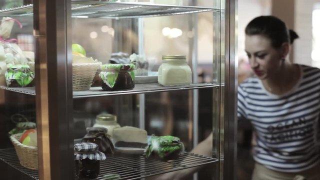 Waiter open the door of fridge and take a cake for customers