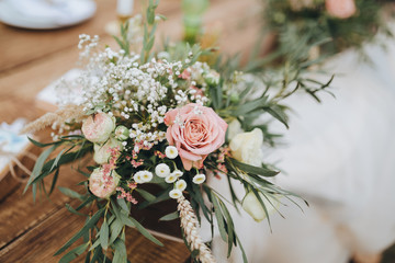 The composition of flowers and greenery is on a festive table in the area of wedding party