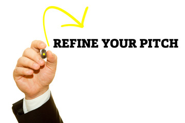 Hand writing REFINE YOUR PITCH with a marker on transparent wipe board.