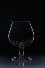 An empty glass on a dark background with reflection and rendering