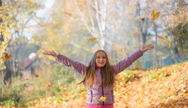 Счастливый подросток девочка в осеннем лесу подбрасывает вверх листья 