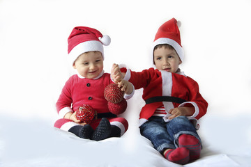 two kids with Santa Claus costume playing with ornaments