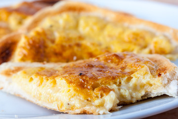 Close-up of a slice of welsh rarebit, a type of cheese on toast, with a bite taken out of it