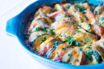 vegetable casserole in a blue bowl on a white background 