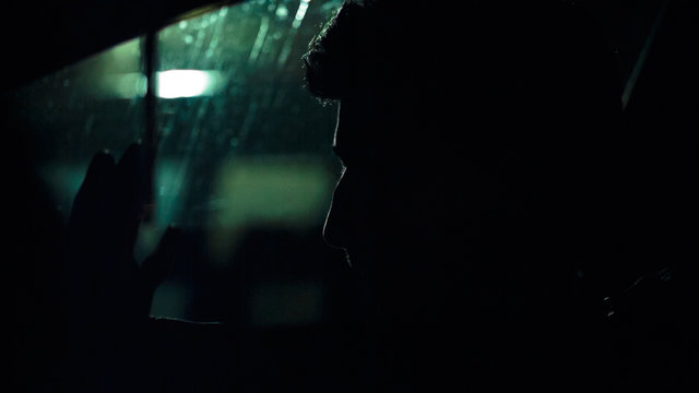 Profile of a man in a car on a dark night. Noir style