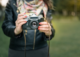 Woman hand holding retro camera close-up on background of autumn