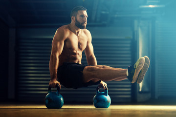 Young man is training by kettlebell. - obrazy, fototapety, plakaty