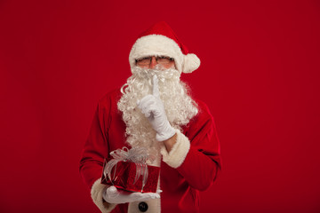 Photo of kind Santa Claus giving xmas present and looking at cam