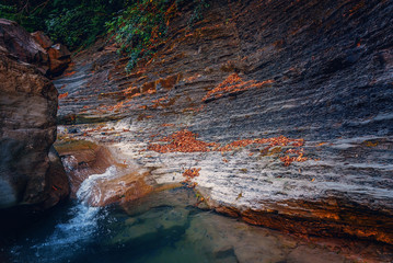 Small waterfall on a river next to a cliff