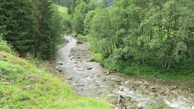 Gerlos Tyrol/ Austria JULY 27 2016: man walking through cold water stream and fly fishing at zillertal, European alps.