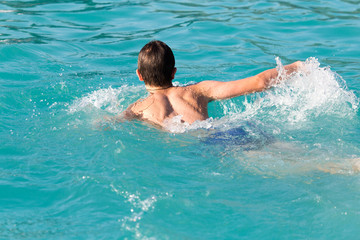 Fototapeta na wymiar boy swims with a splash in the water park