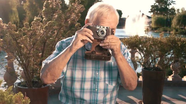 Senior man with camera. Elderly male outdoor. Grandpa found a new hobby. Impressive photos of nature.